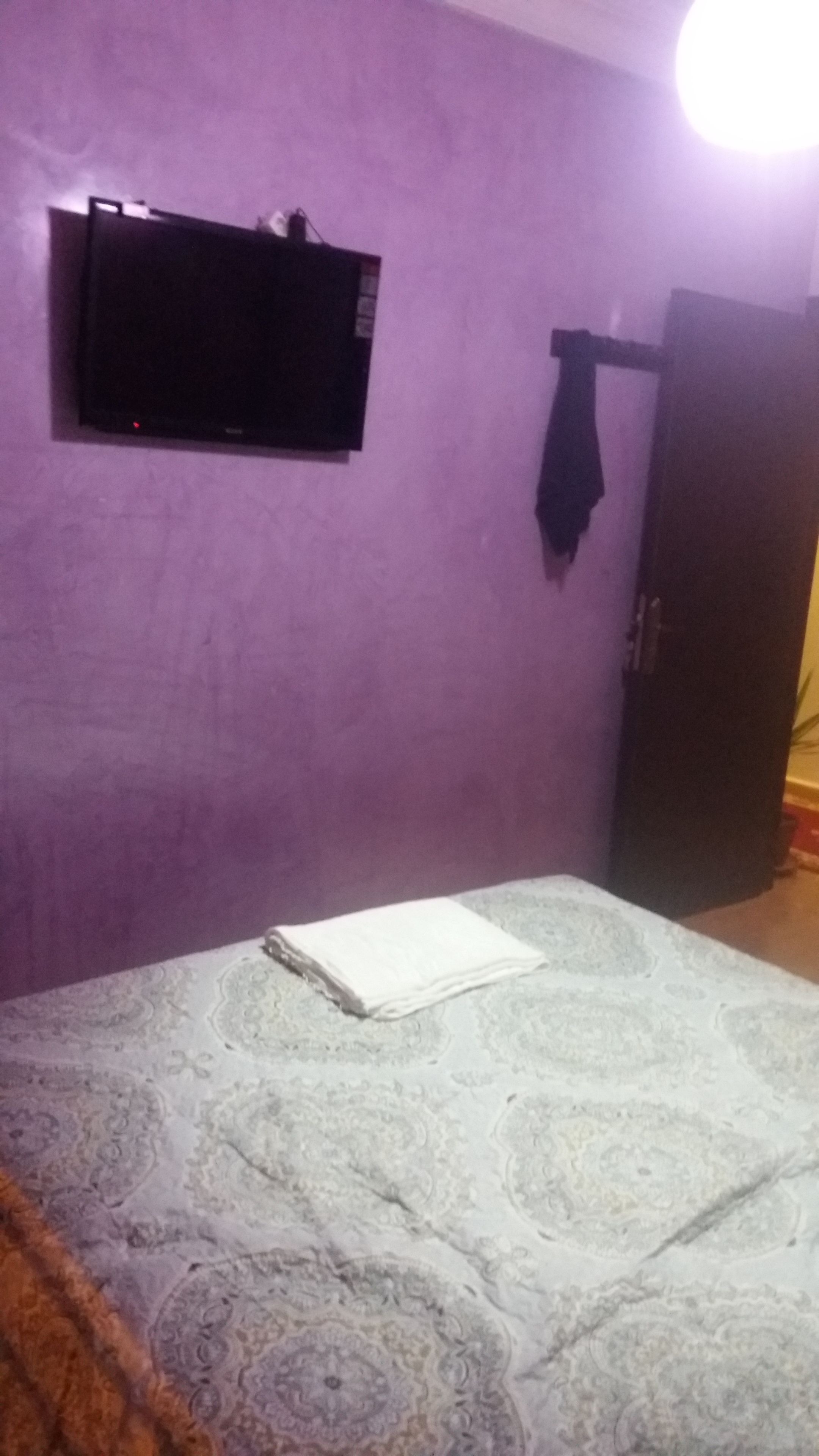 A room with a bed, a television mounted on the wall, and a wardrobe.