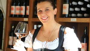 A person holding a wine glass in front of a wine rack. - Hotel Hirschen Glottertal (Glottertal)