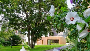 A modern building with large windows and a well-maintained lawn. - Hotel Hirschen Glottertal (Glottertal)