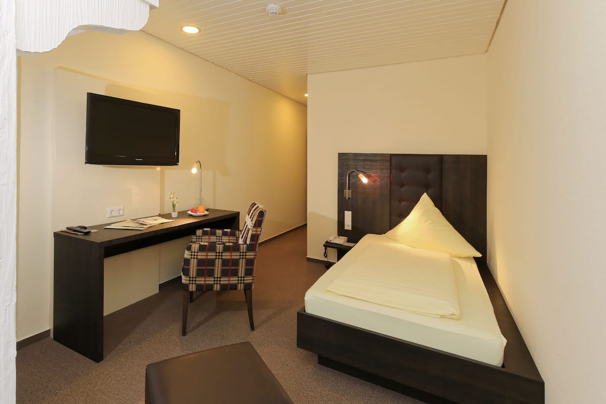 Een hotelkamer met een bed, een bureau, een stoel, een televisie en een nachtkastje.