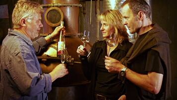 A group of people in a dimly lit room with industrial elements like metal tanks and pipes.