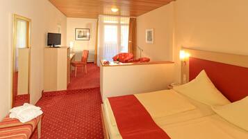 Een hotelkamer met een bed, een bureau, een stoel en een televisie.