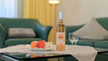 A table with a bottle of wine, a glass, and a plate of apples in a hotel room.