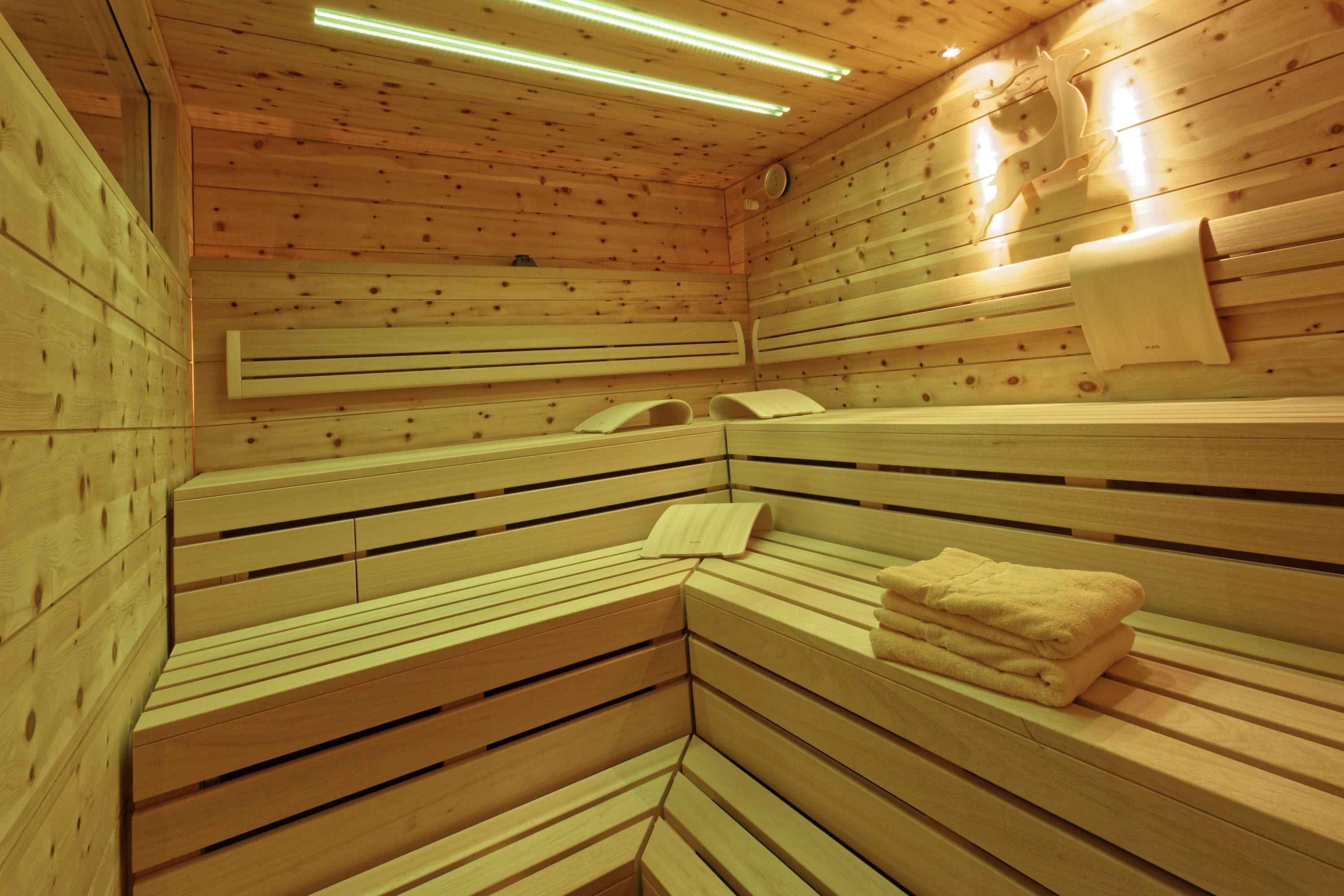 Una sauna con panche in legno, un portascopevoli e un riscaldatore a parete.