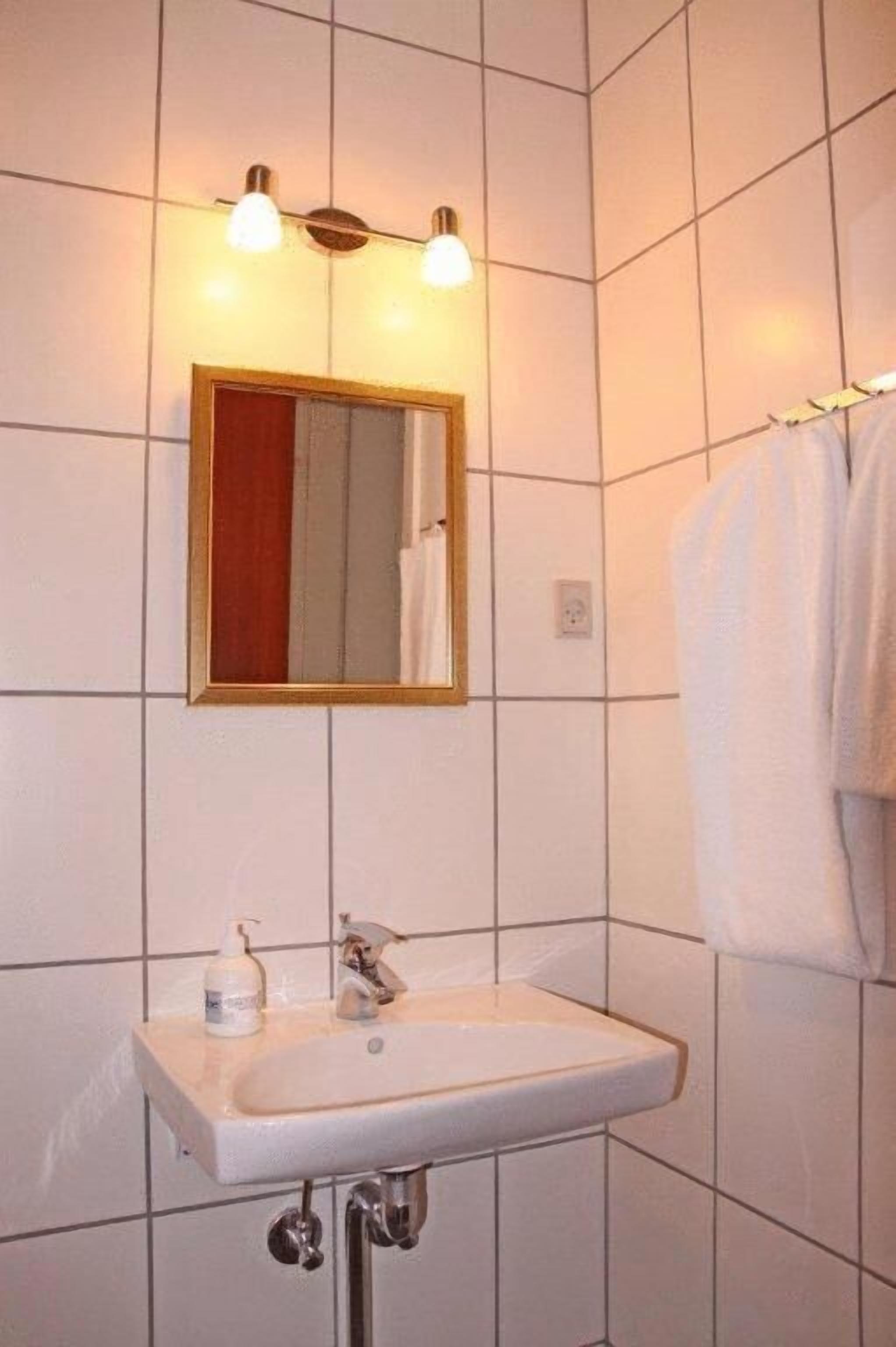 A bathroom with a white sink, a mirror with a wooden frame, and a towel hanging on the wall.