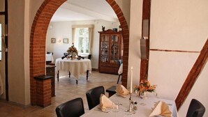 Un comedor con un arco de ladrillo, una mesa puesta para dos personas y un aparador al fondo.