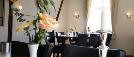Un comedor con una mesa, sillas, un florero con flores, una vela y luces fijadas a la pared.