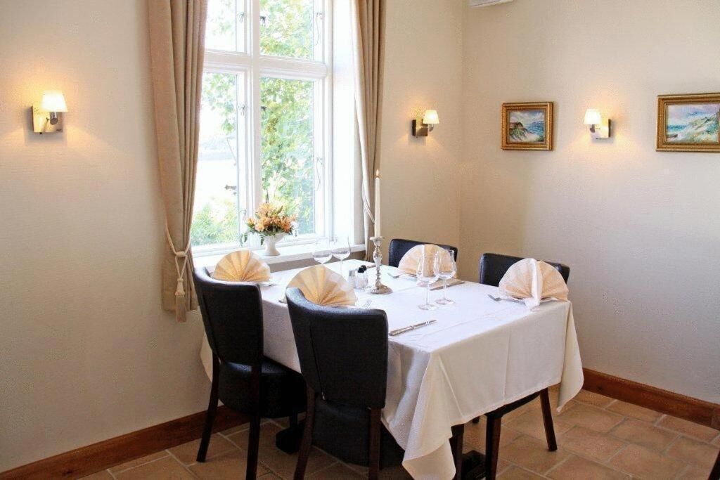 Ein Essbereich mit Tisch für vier Personen, Stühlen und einem Fenster mit Vorhängen.