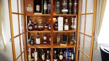 A wooden liquor cabinet with multiple shelves containing various bottles of alcohol.