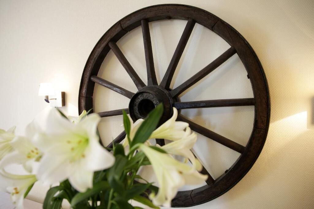 A wall-mounted wooden wheel with a flower arrangement in front.