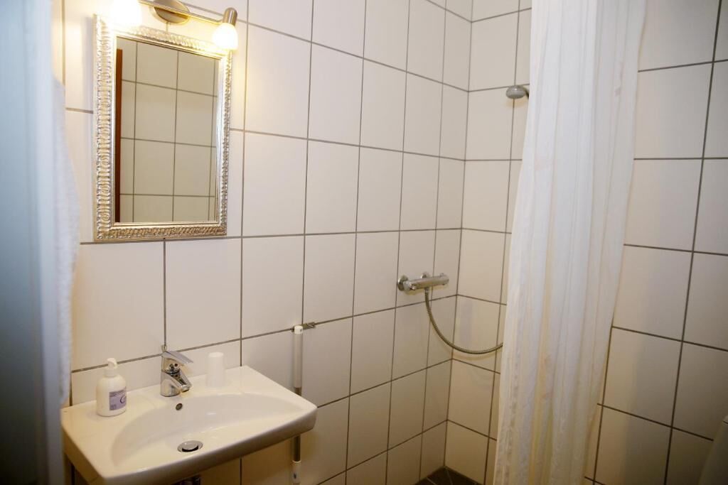 A bathroom with a sink, mirror, and shower.