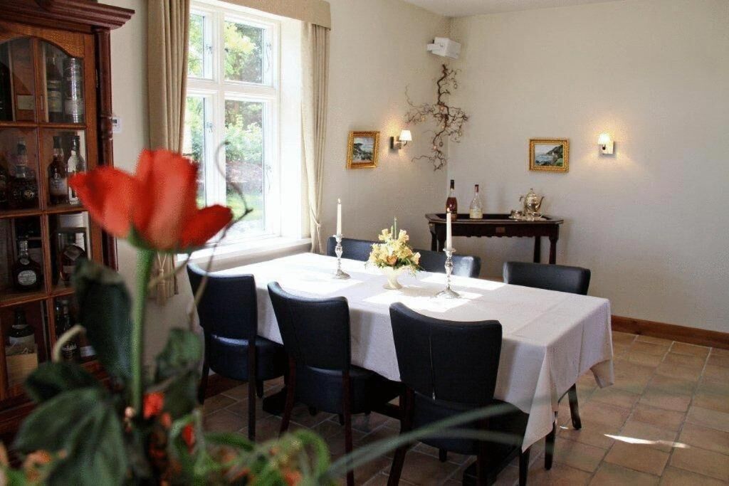 Comedor con una mesa preparada para cuatro personas, sillas, un aparador con botellas e iluminación en la pared.