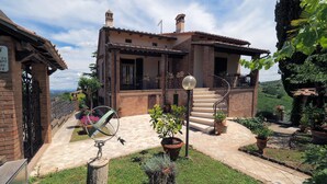A rustic villa with a stone facade, a spiral staircase, and a garden with potted plants and flowers. - Fireplace, apartment with veranda and view of San Gimignano (San Gimignano)