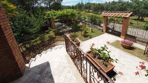 A balcony with a view of a garden, a pergola, and a tiled floor. - Fireplace, apartment with veranda and view of San Gimignano (San Gimignano)
