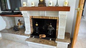Une cheminée agrémentée d’objets décoratifs, un téléviseur posé sur une  étagère au-dessus, et une porte sur la droite.