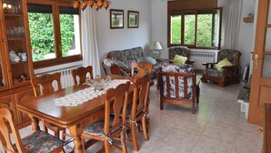 Un coin repas comprenant une table et des chaises en bois, un canapé et un meuble contenant de la verrerie.