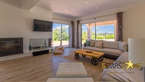 A spacious living room with a large sofa, a wooden coffee table, and a flat-screen TV mounted on the wall. - The Land, Villa-Finca 5StarsHome Mallorca (San Jordi)