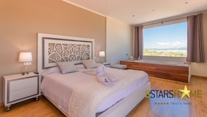 A modern bedroom with a large bed, a nightstand, a bedside table, a window with a view, and a decorative headboard. - The Land, Villa-Finca 5StarsHome Mallorca (San Jordi)