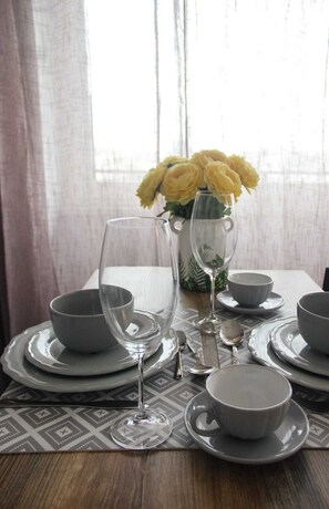 A dining table set with plates, bowls, a wine glass, and a vase with yellow flowers. - Sunny City Center Apartment (Warsaw)