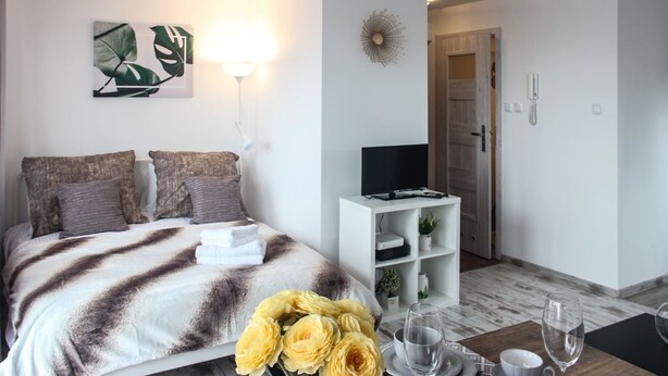 Une chambre moderne comprenant un lit, une table de chevet, une télévision et une étagère fixée au mur.