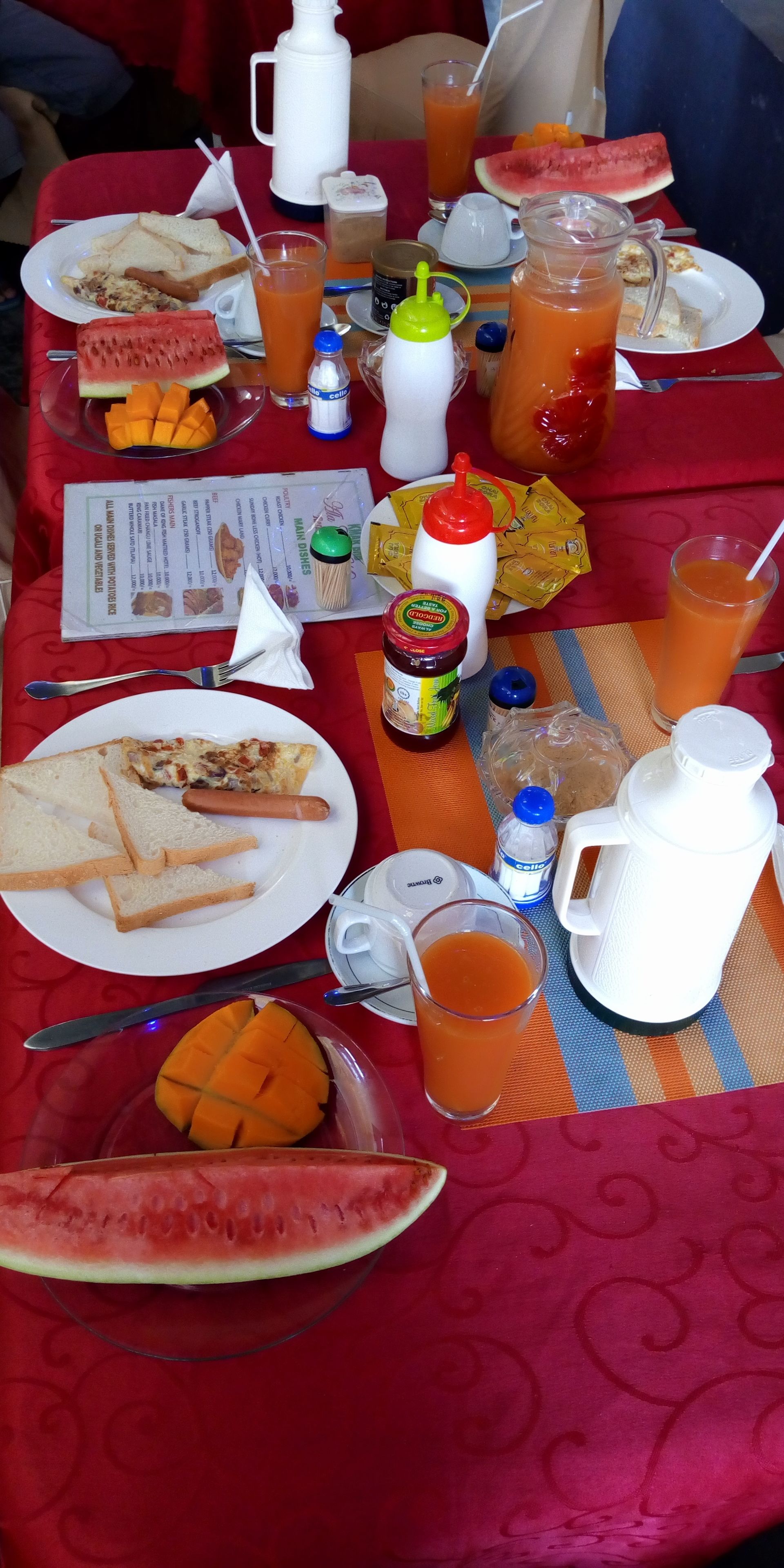 Una mesa de desayuno con diversos alimentos, bebidas, salsas y un menú.