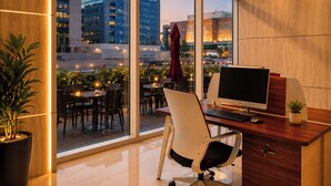 A modern office space with a large window, a desk with a computer, and a view of the cityscape.