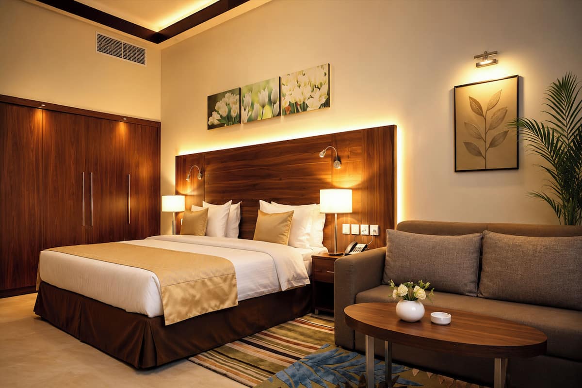A hotel room with a bed, a sofa, a coffee table, a nightstand, and artwork on the walls.