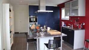 Una cucina moderna con isola centrale, elettrodomestici in acciaio inossidabile e una parete d'accento rossa.