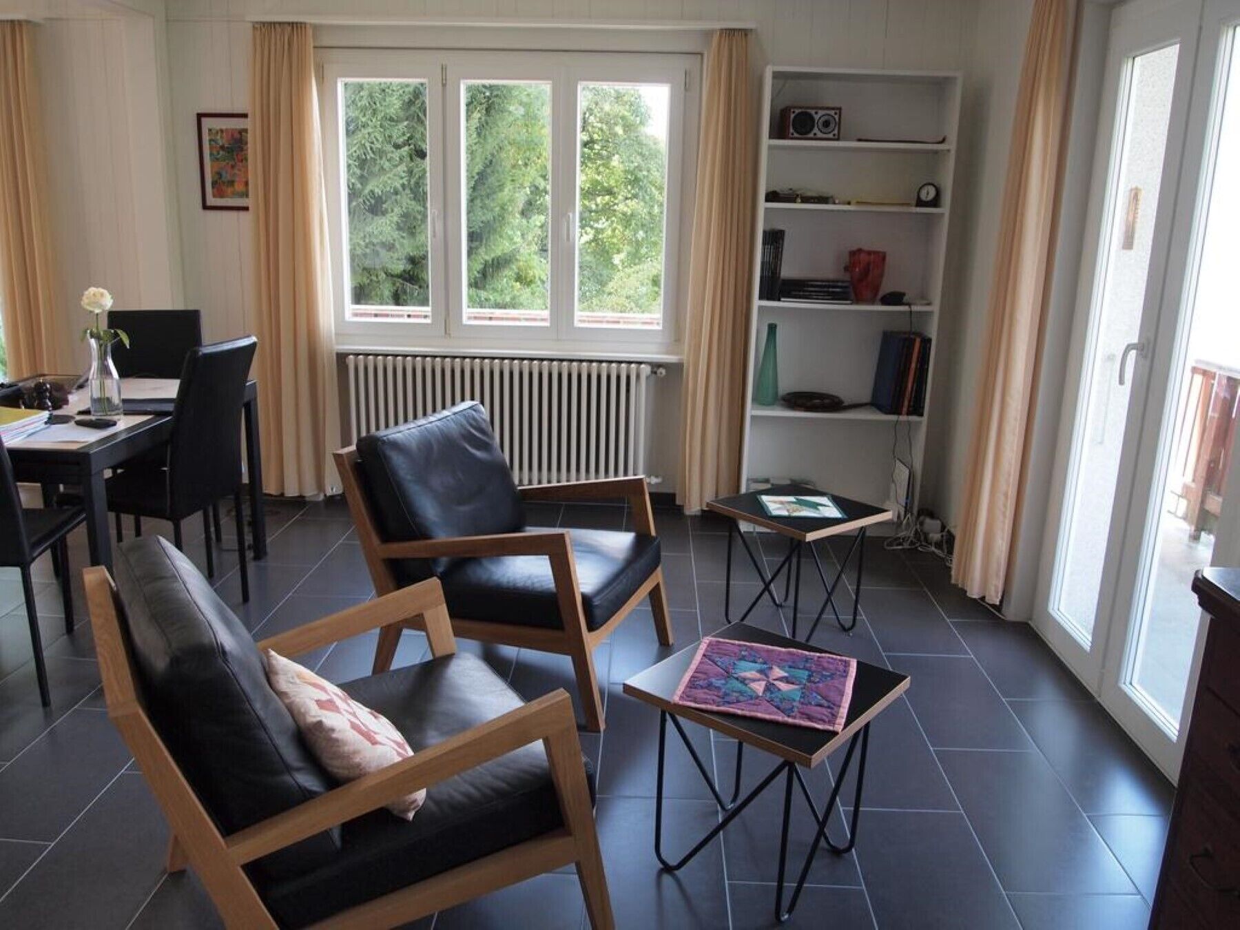 Ett modernt vardagsrum med en soffa, en fåtölj, ett litet bord och en bokhylla.