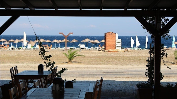 A beachside restaurant with outdoor seating, a view of the beach, and umbrellas. - Metis Bungalow (Ayvacik)