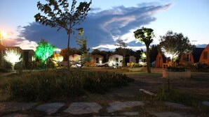 A courtyard with stone pathways, trees, and several small, orange-roofed structures. - Metis Bungalow (Ayvacik)