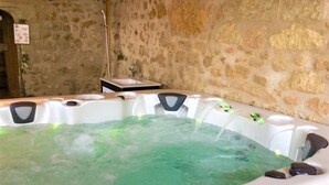 Un jacuzzi con un muro de piedra de fondo y una pequeña mesa con un lavamanos.