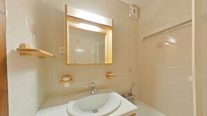 A bathroom with a white sink, a mirror, and a shower area. - Cozy 2-Room Apartment for 5 with Ski Storage and Garage in Le Grand-Bornand (Le Grand-Bornand)