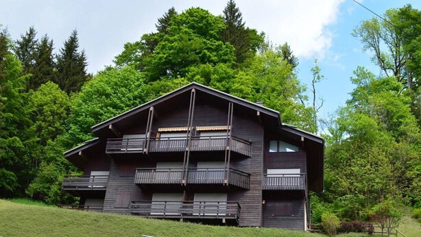A modern multi-story building with balconies, surrounded by lush greenery and trees. - Cozy 2-Room Apartment for 5 with Ski Storage and Garage in Le Grand-Bornand (Le Grand-Bornand)