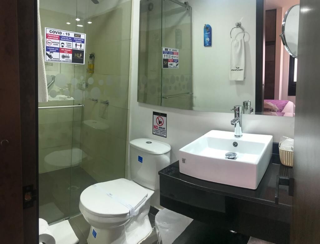 A modern bathroom with a glass shower enclosure, a white toilet, and a black vanity with a white sink.
