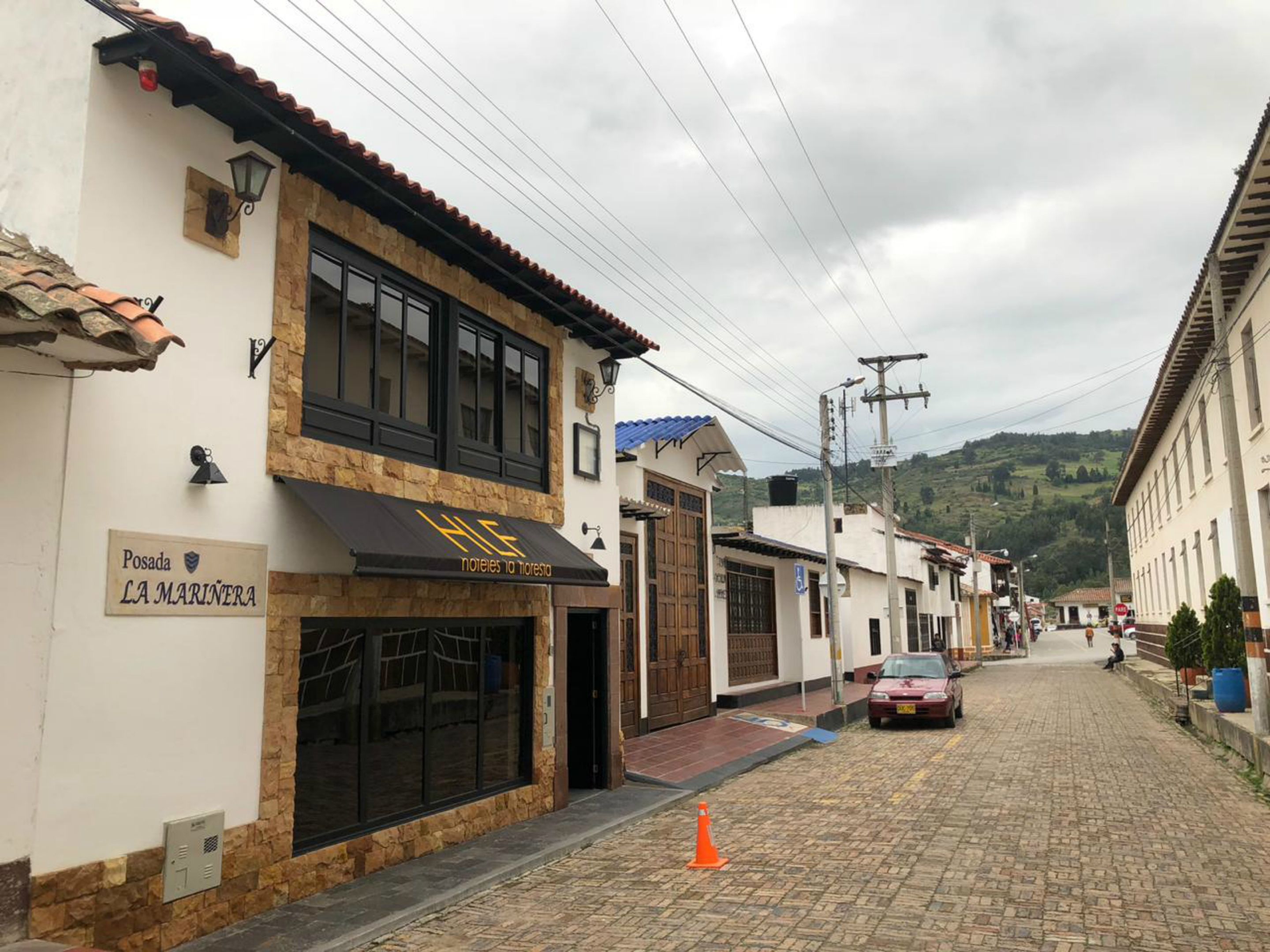 Uma rua de paralelepípedos com um hotel chamado "Posada LA MARINERA" à esquerda.