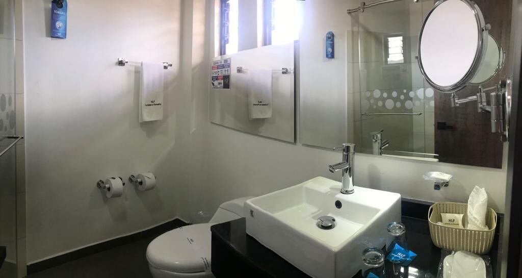 Une salle de bain moderne avec un lavabo blanc, un miroir et des toilettes.