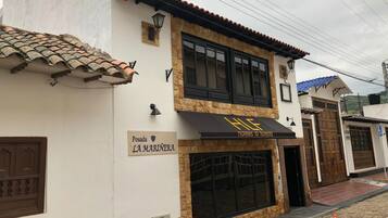 A two-story building with a sign for 'Posada La Marinería' and a black awning with 'HLE' logo.