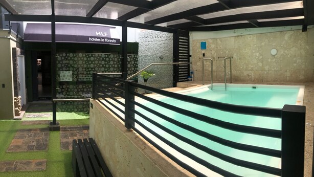 Una piscina interior con un fondo de pared de piedra, una terraza de madera y un letrero que dice 'HILF hoteles la floresta'.
