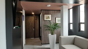 Un moderno vestíbulo de hotel con un sofá, una planta en maceta y cuadros en la pared.