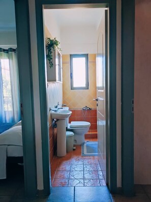 A narrow hallway leading to a bathroom with a toilet, sink, and shower. - Nefeli City Apartments (Patras)