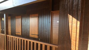 Un balcón de madera con barandilla, que cuenta con varias ventanas con contraventanas de madera.