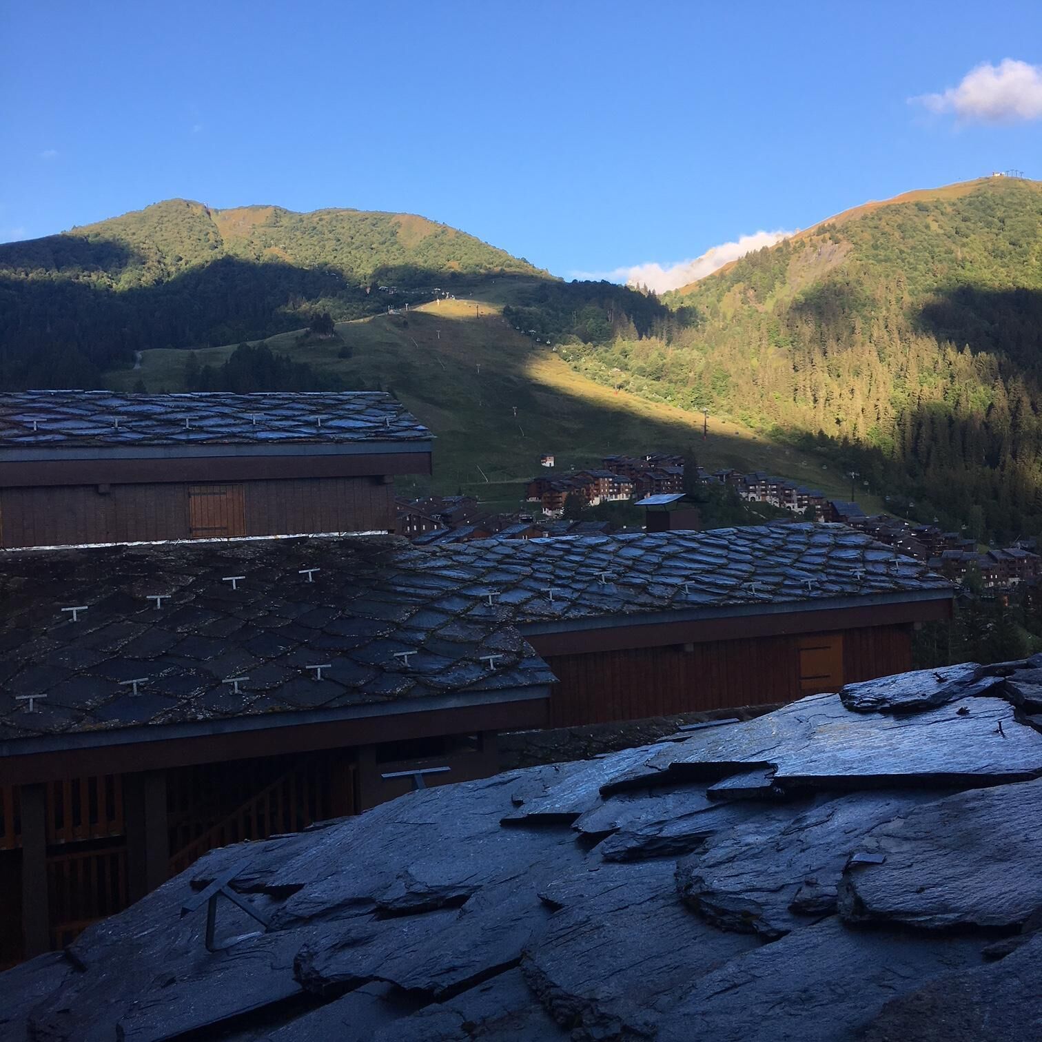 Eine gebirgige Landschaft mit einer Ansammlung von Gebäuden mit geneigten Dächern, vermutlich eine Lodge oder ein Resort.