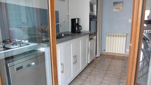 A kitchen with white cabinets, a stainless steel stove, a coffee maker, and a radiator. - House near the African reserve (Sigean)