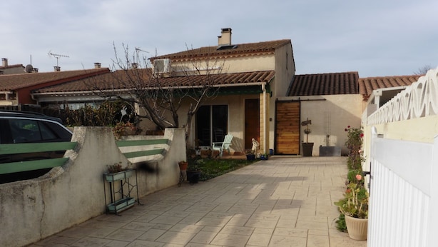 A residential property with a tiled patio, a car parked in the driveway, and a white fence. - House near the African reserve (Sigean)