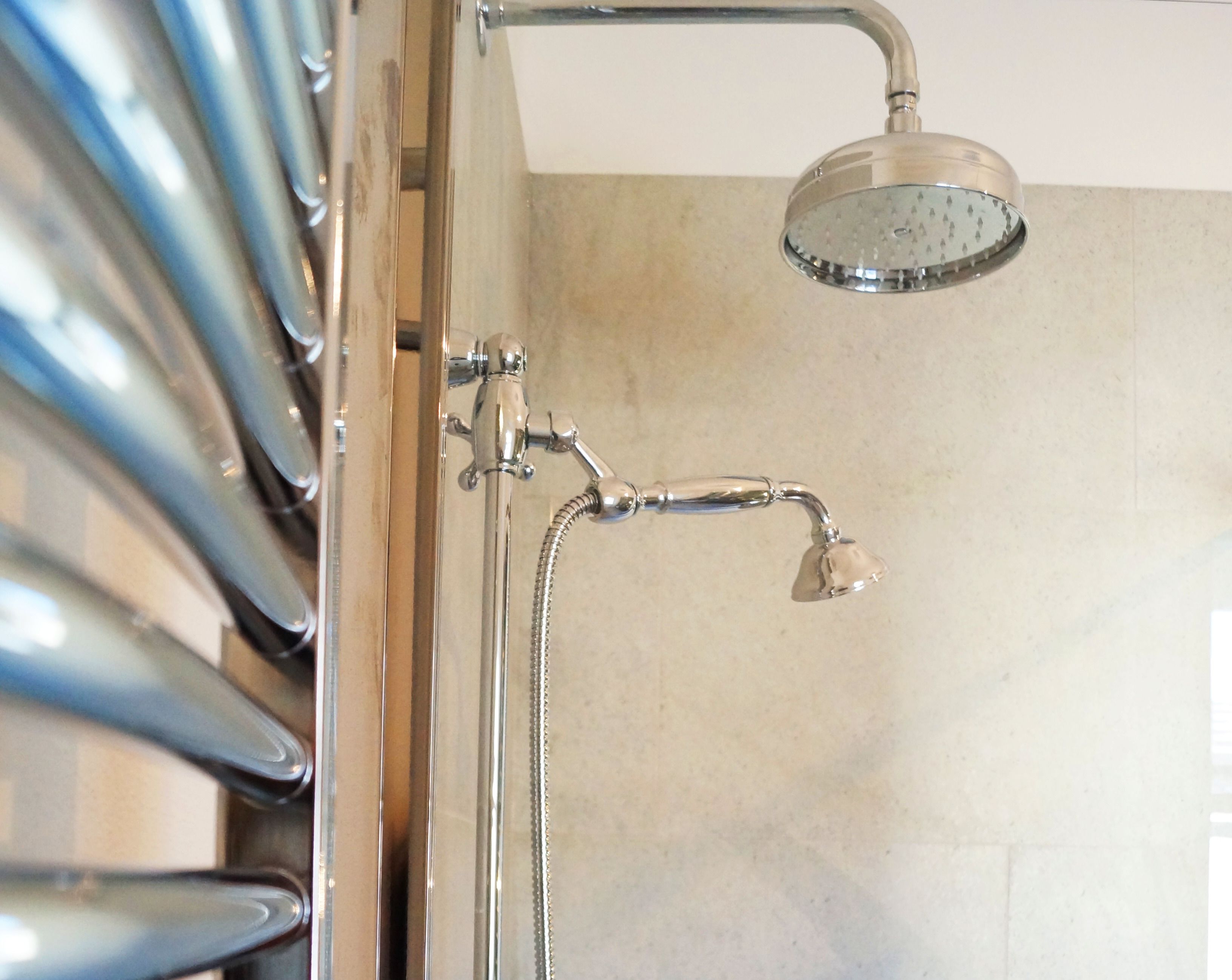 A shower with a handheld showerhead and a fixed overhead showerhead.