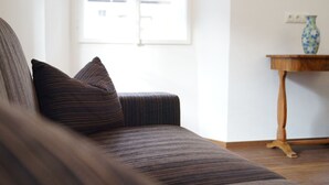 Un salon avec un canapé à rayures sombres, une table d’appoint en bois et un vase.