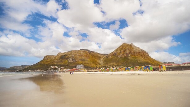 A beach with colorful beach huts, a mountain in the background, and a clear sky. - Summer vacation in Cape Town, South Africa (Plumstead)
