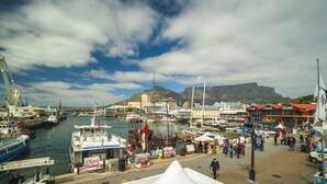 A harbor with boats, a large building, and a mountain in the background. - Summer vacation in Cape Town, South Africa (Plumstead)