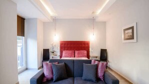 A modern bedroom with a large bed, a blue sofa, and two speakers. - Riviera Luxury Suites B&B (Naples)